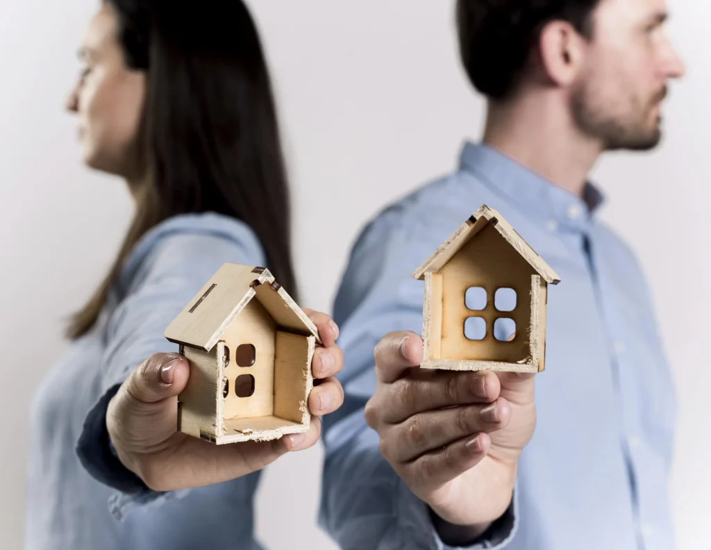 Pareja sosteniendo dos casas de madera que representan un proindiviso
